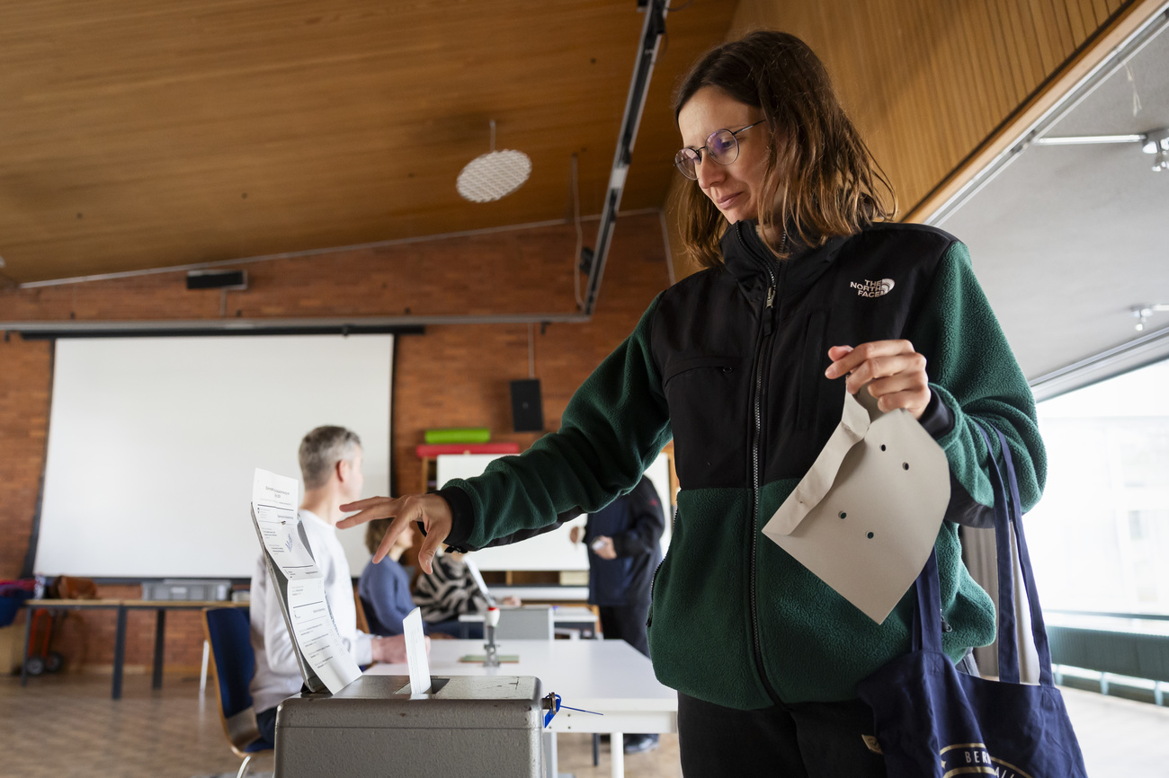 Una donna deposita una scheda in un'urna elettorale.