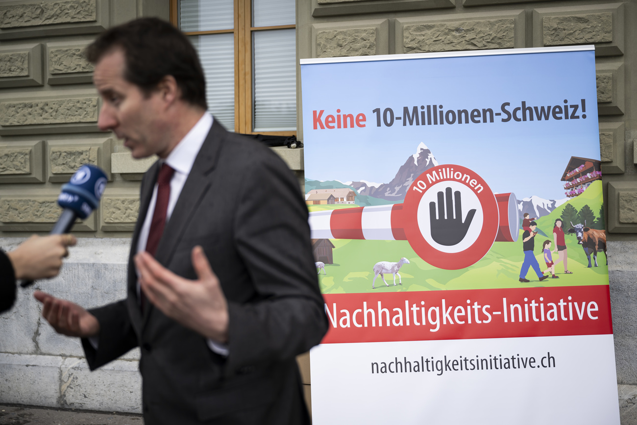 Thomas Aeschi from Swiss People's Party speaking in an interview in front of posters promoting the initiative