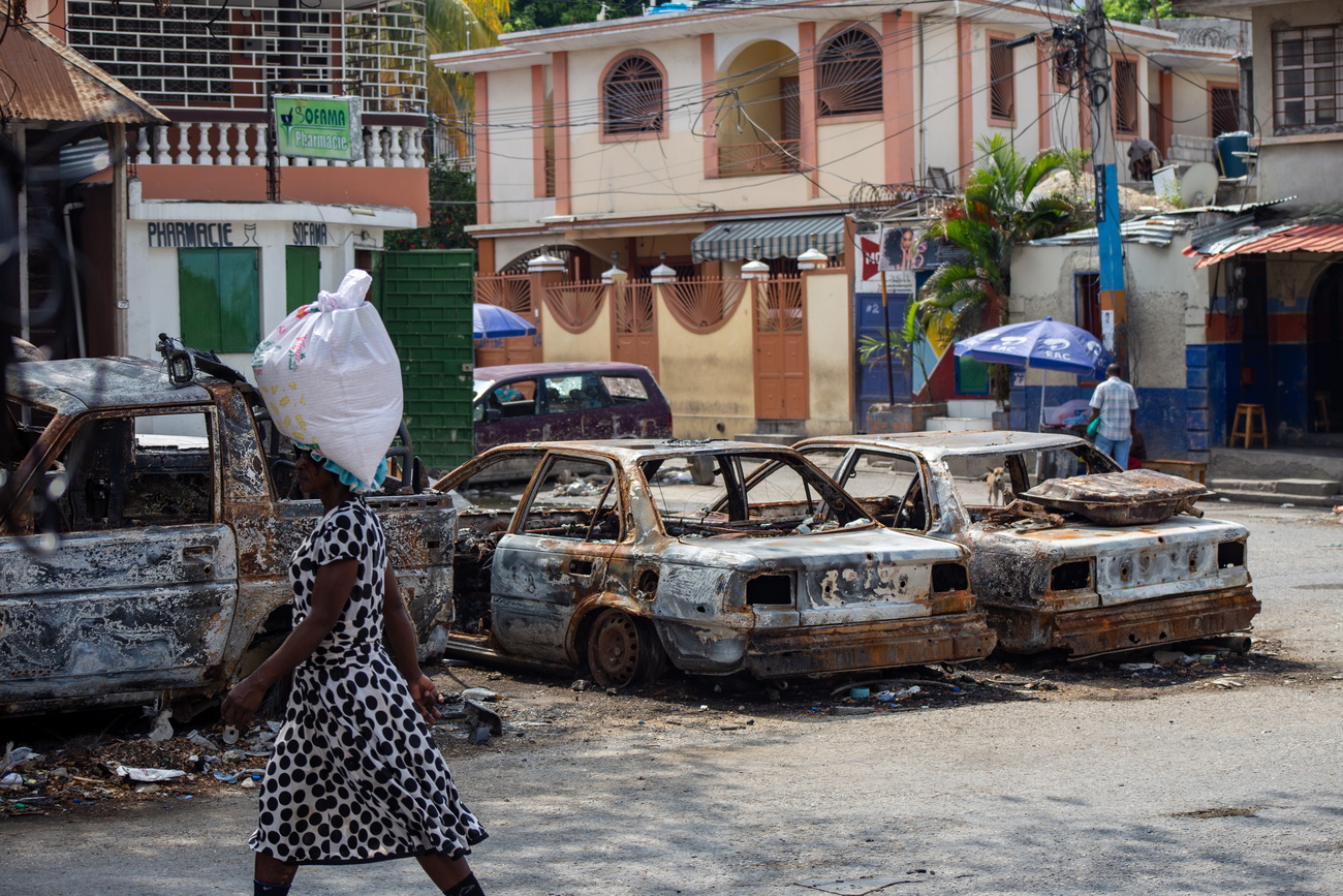 Una mujer pasa junto a los restos de vehículos quemados en el centro de Puerto Príncipe el 6 de abril.