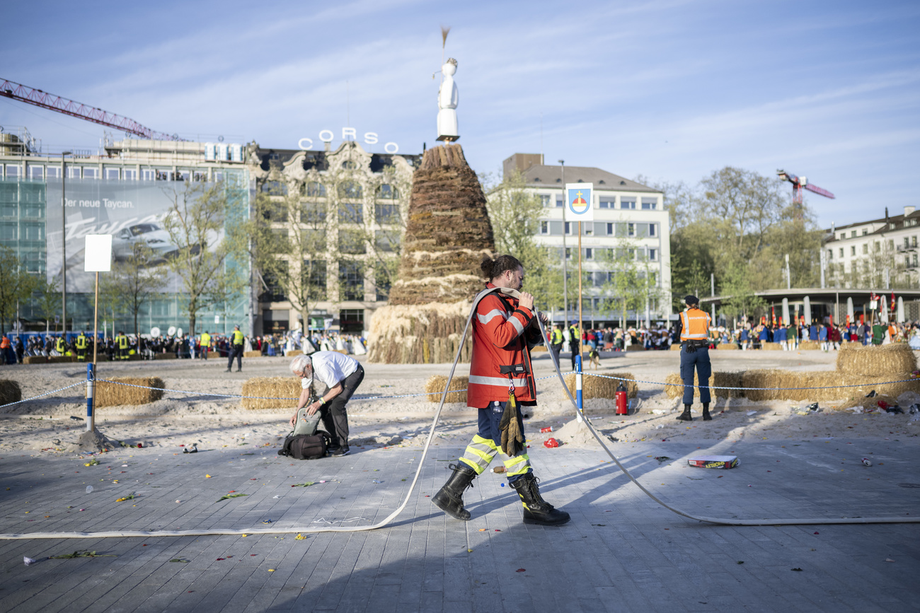 A man from the fire brigade carries a fire hose away in the front of the "Boeoegg" during the Sechselaeuten place in Zurich, Switzerland, pictured on April 15, 2024. The Sechselaeuten (ringing of the six o'clock bells) is a traditional end of winter festival with a parade of guilds in historical uniforms on horseback and the burning of the Boeoegg, a symbolic snowman, at 6 pm. The faster the Boeoegg explodes, the hotter the summer will be according to traditional weather rules