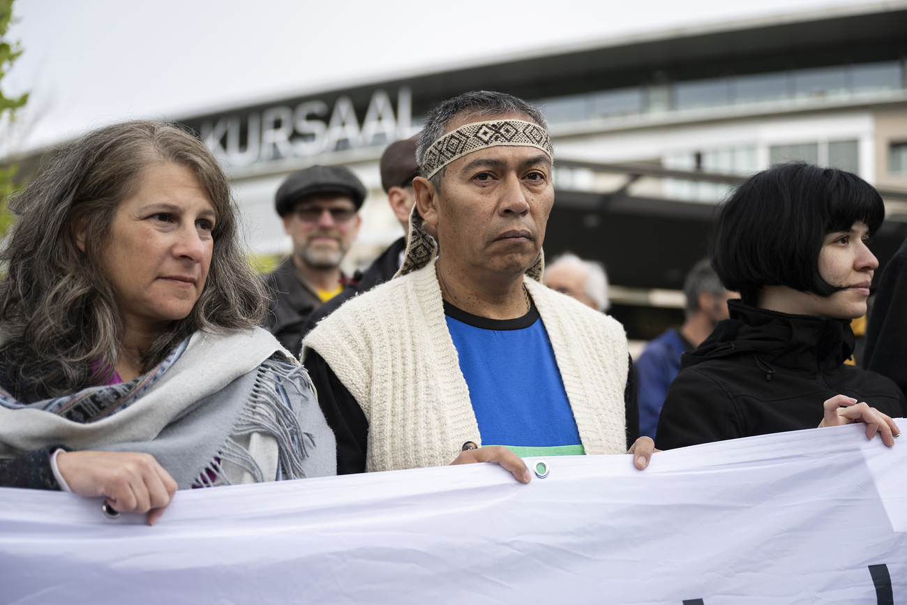 Two women and one man hold a cloth banner at a protest.