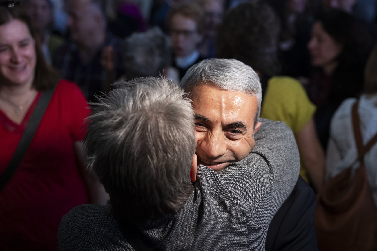 Mann, der lacht, wird von einer anderen Person herzlich umarmt