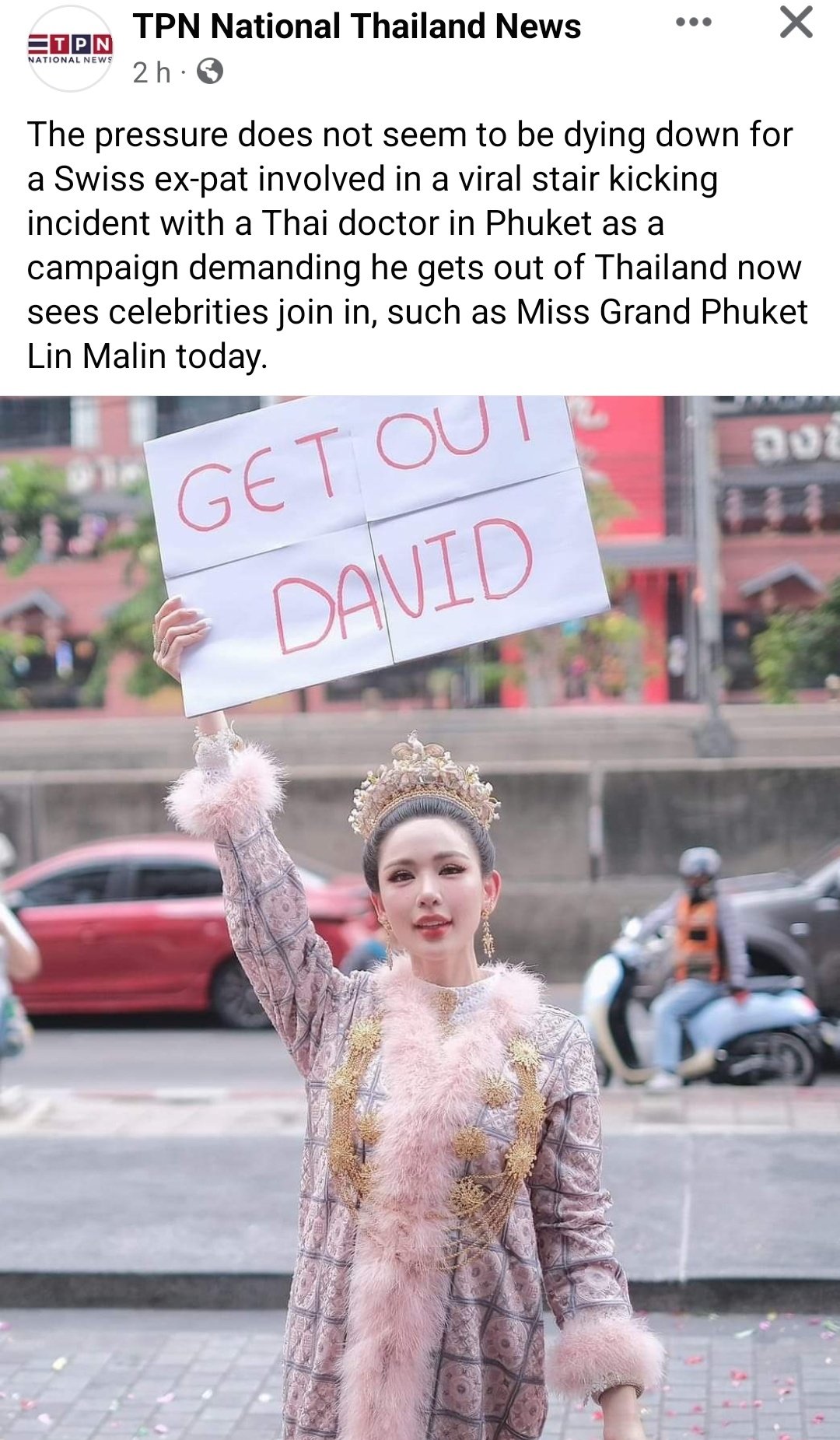una donna thailandese tiene in mano un cartello che dice "vattene david"