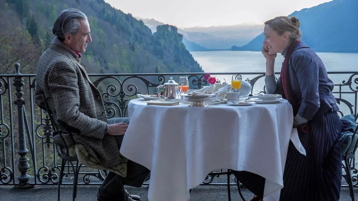 Zwei Menschen auf einem Balkon, im Hintergrund ein See