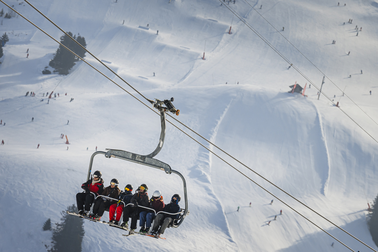 Sechs Skifahrer:innen auf einem Sessellift in einem Schweizer Wintersportgebiet