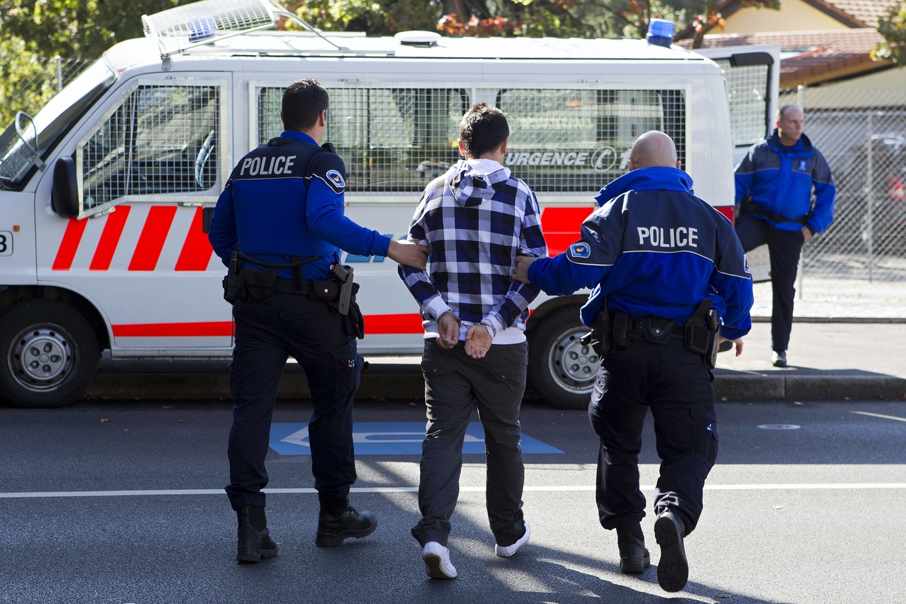 Un uomo ammanettato tra due poliziotti.