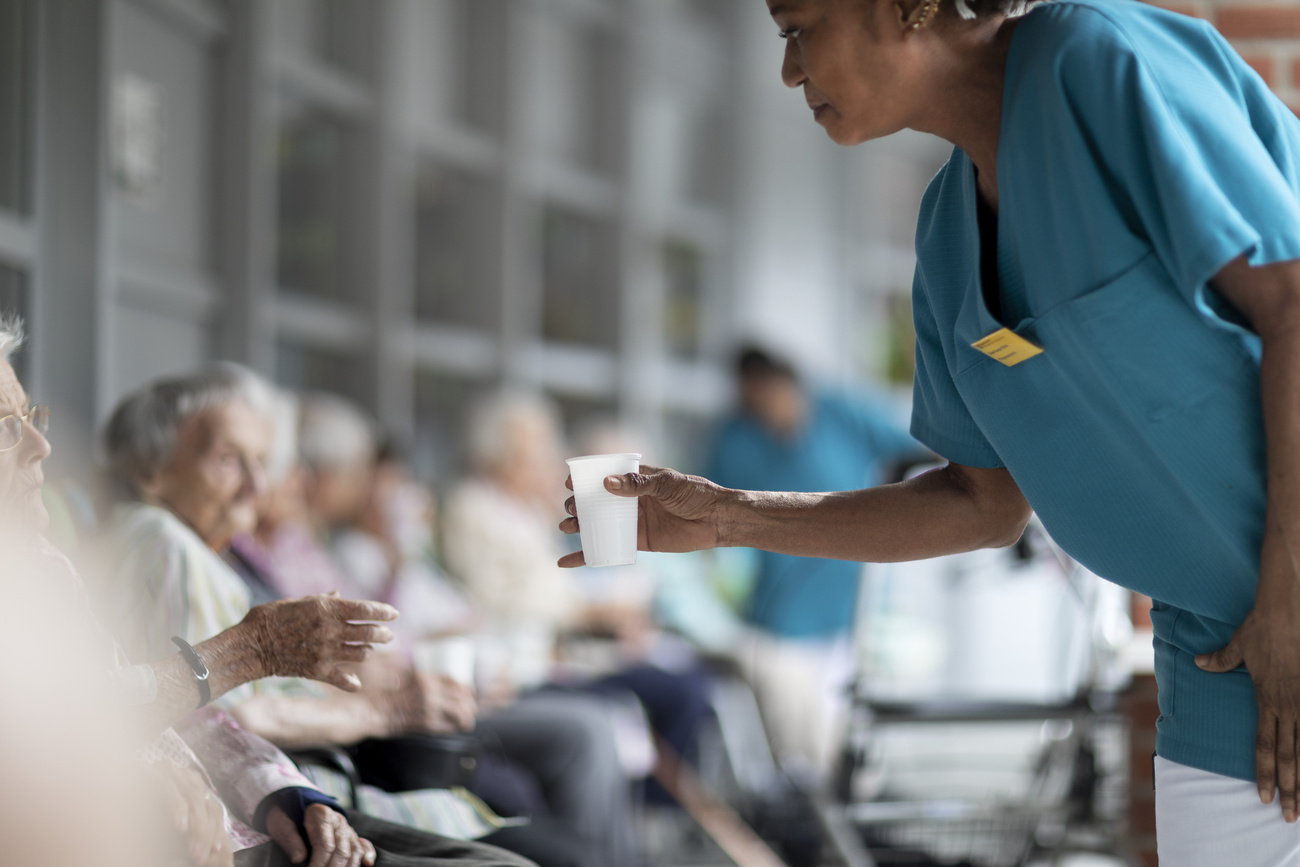 Una auxiliar de enfermería distribuye agua como medida preventiva contra posibles consecuencias del calor a los residentes del centro de atención para personas mayores Herzogenmuehle.