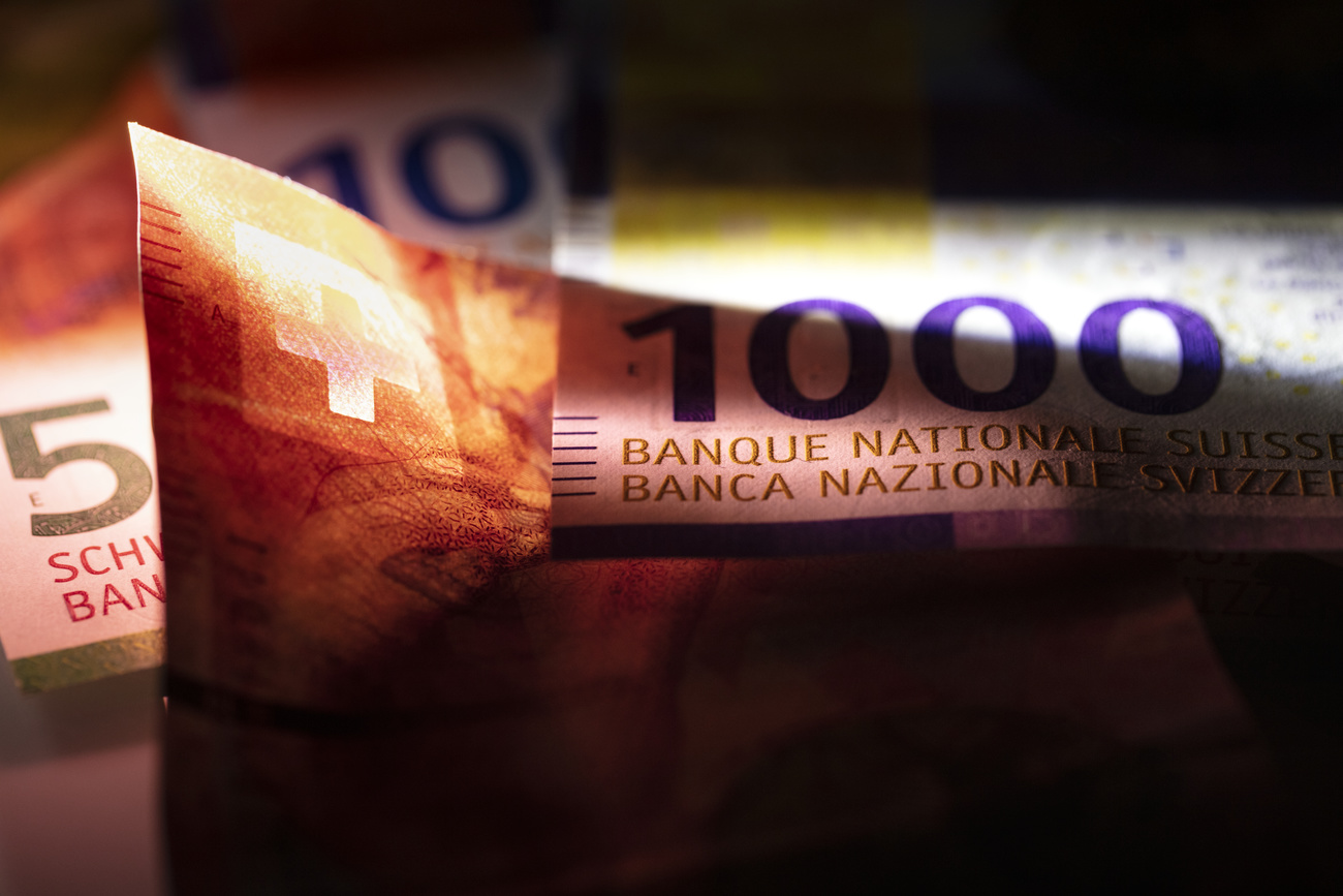 Detail view of a thousand Swiss franc note from the nineth Swiss banknote series. The edges of the photo are dark but the purple 1,000 and the red Swiss flag are spotlighted.