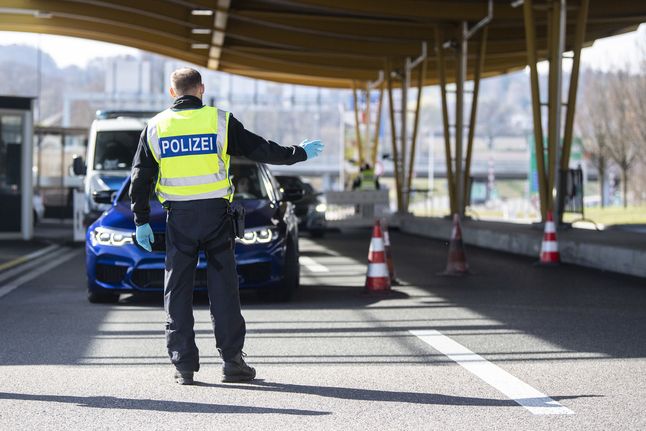 Un agente ferma un'auto a un valico doganale.