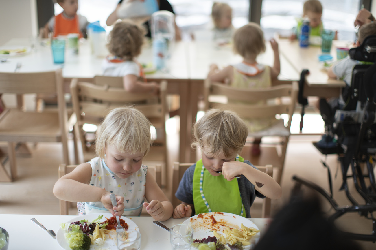 young children wearing bibs eating in day care
