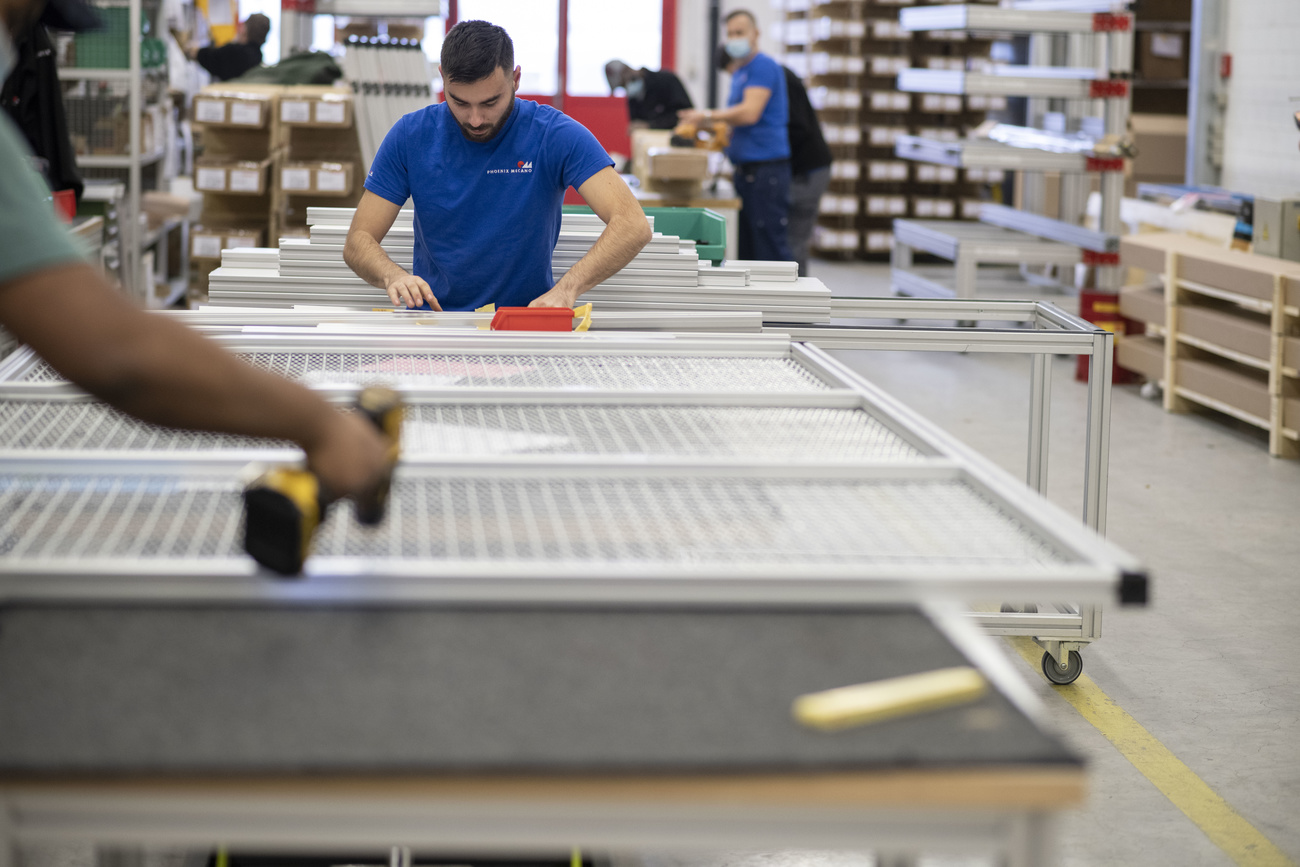 Employees at Phoenix Mecano assemble protective and partitioning systems in the production hall.