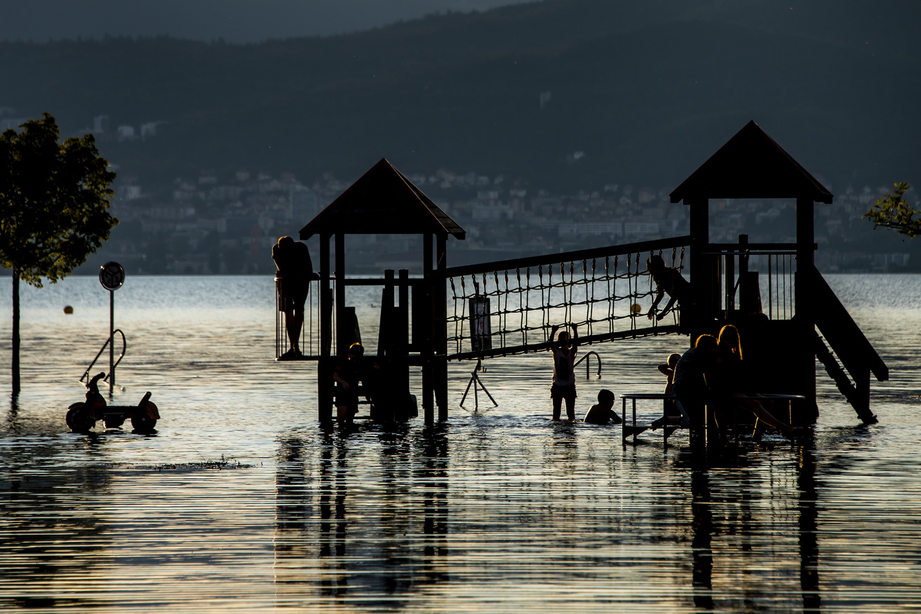example of urban flooding. Children have fun on a flooded playground surrounded by the water of Lake Neuchatel in the port of Cudrefin following heavy rainfall in recent days on Friday July 16, 2021 in Cudrefin in the canton of Vaud.