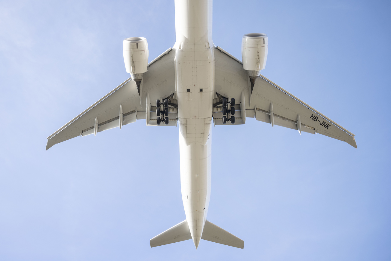 The white underside of a Boeing 777-300E plane against a light blue sky.