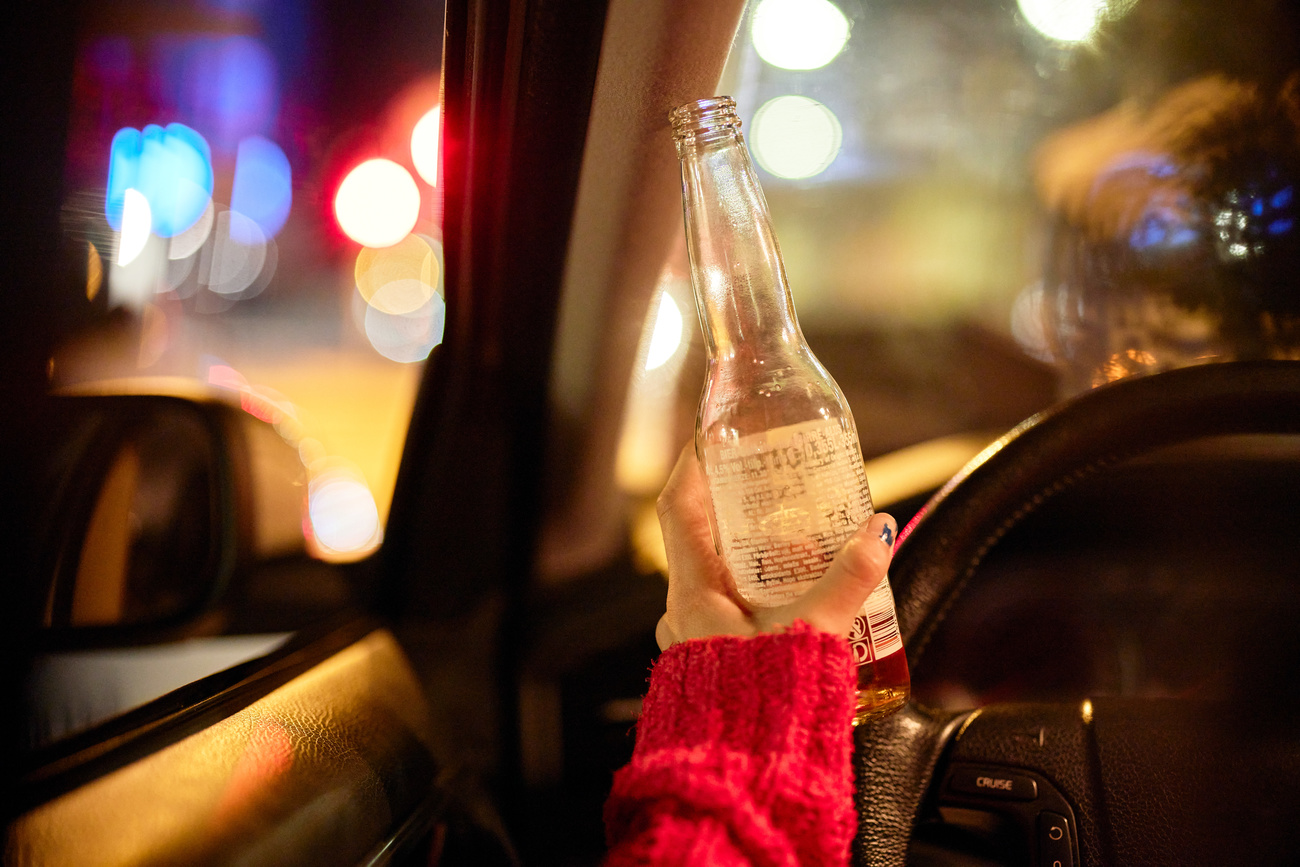 (symbolic picture) a young person's hand holding a beer bottle while driving
