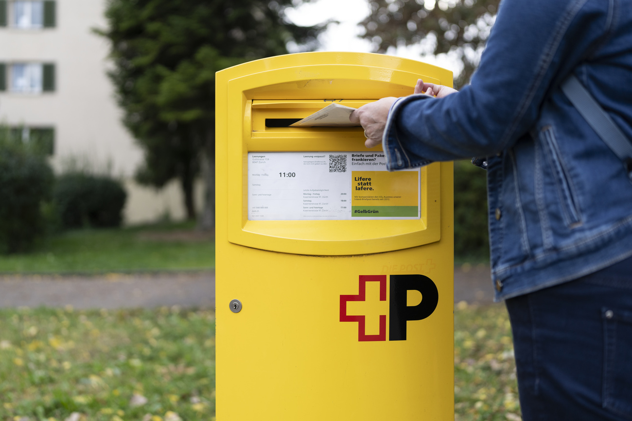 Eine Frau wirft einige Briefe in ein Briefkasten