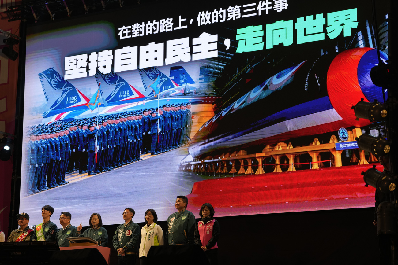 Taiwan's President Tsai Ing-wen speaks on the podium near a display showing Taiwanese fighter jets and submarine with the title "Adhere to Freedom and Democracy, Go Global" during an election rally for the Democratic Progressive Party presidential candidate in New Taipei City, Taiwan on Saturday, Jan. 6, 2024. Using military threats, diplomatic pressure, fake news and financial inducements for politicians, China is deploying a broad strategy to influence voters in Taiwan's elections to pick candidates who favor unification. (AP Photo/Ng Han Guan)