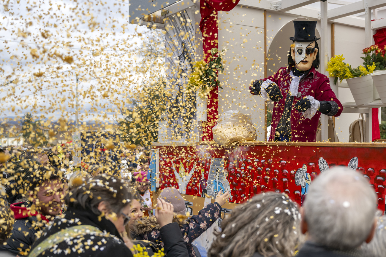 EIn fasnaechtler wirft Raeppli auf die Zuschauer am Cortege an der Fasnacht in Basel, am Montag, 19. Februar 2024. (KEYSTONE/Georgios Kefalas)