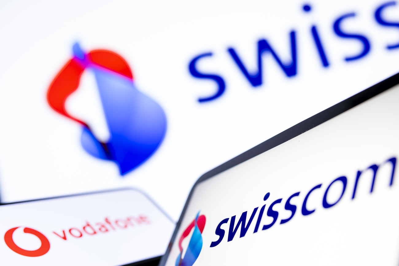 The Swisscom and Vodafone logos side by side: Swisscom is comprised of intertwined red and blue shapes and ‘Swisscom’ in darker blue, while Vodafone is a red circle with a white apostrophe inside.