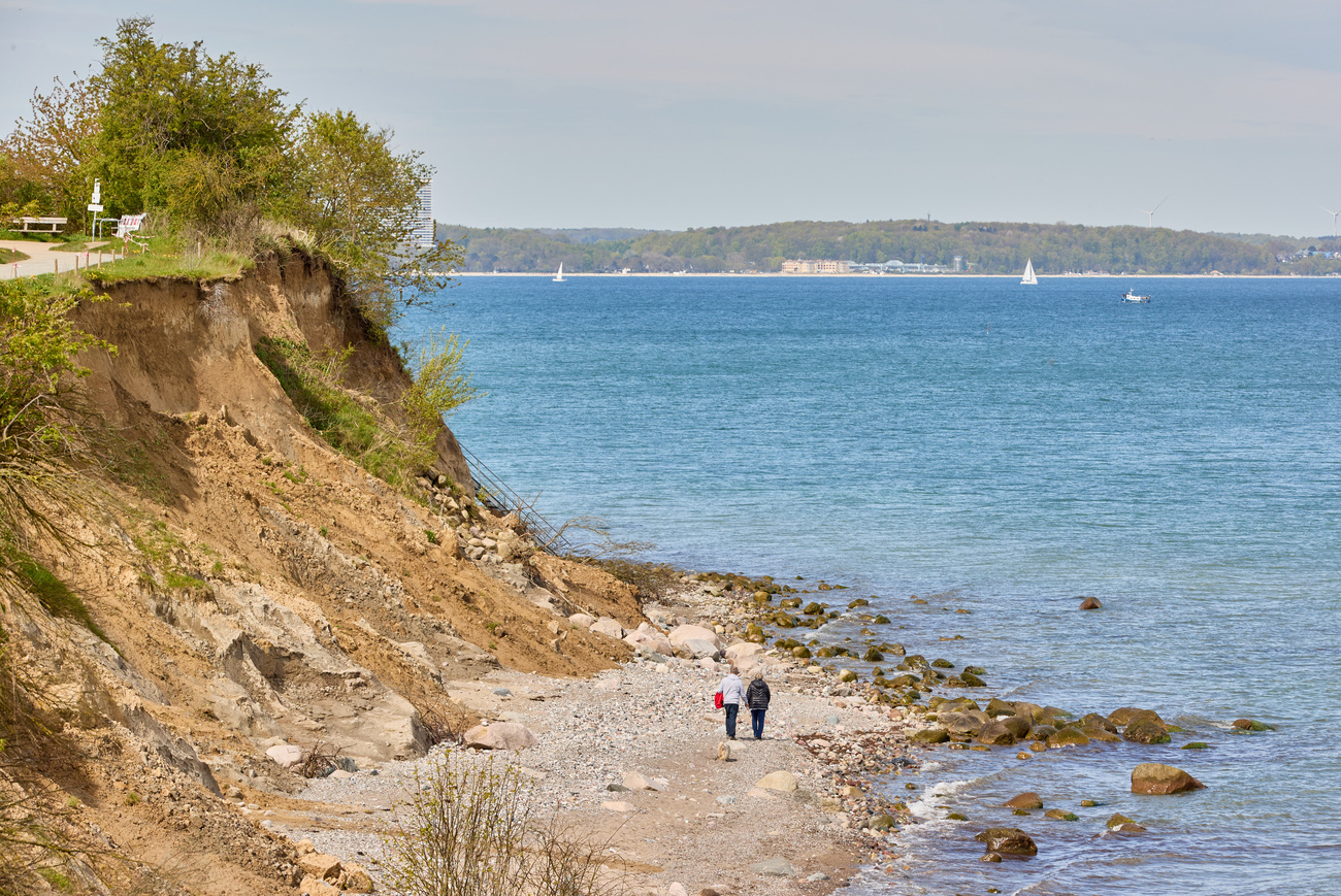 due persone camminano su una costa affacciata sul mare