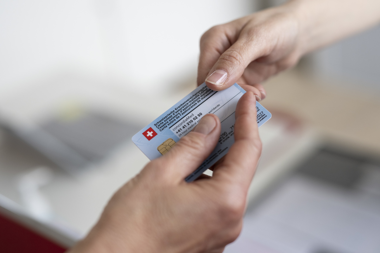 A patient hands over their health insurance card into another person’s hand.