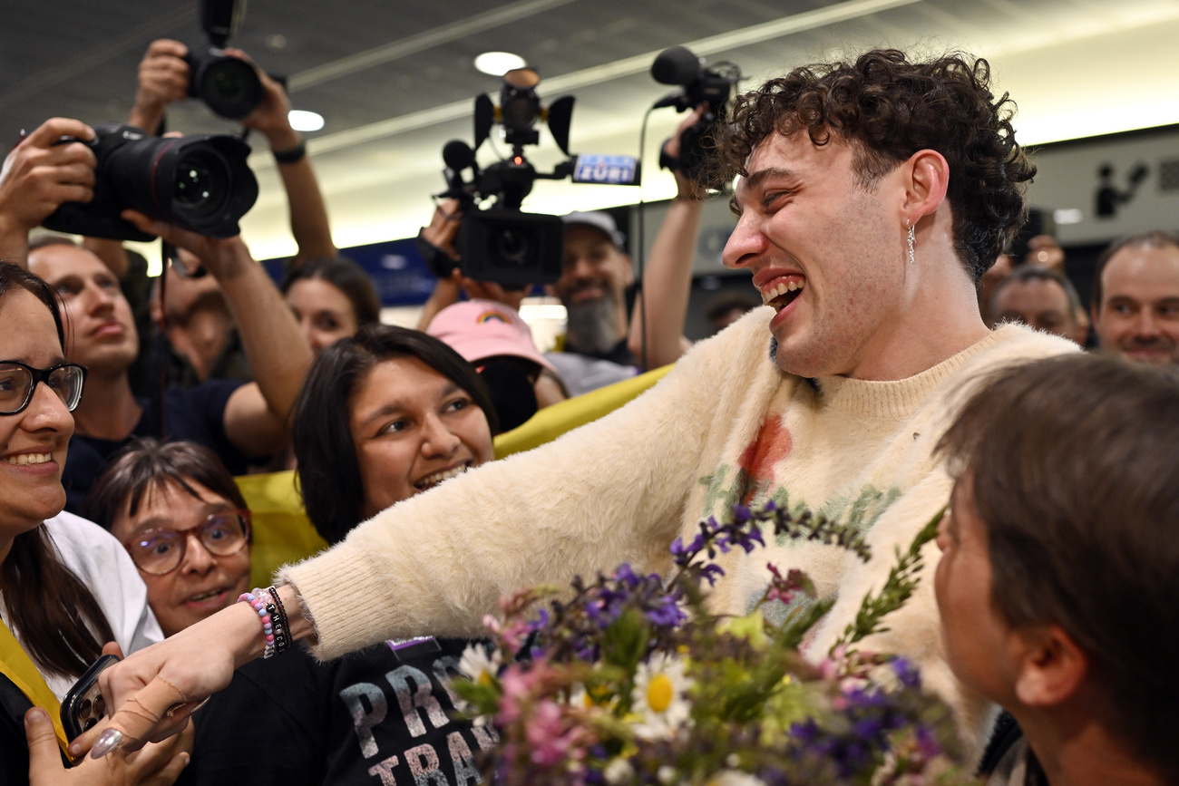 Swiss Singer Nemo, winner of the 68th edition of the Eurovision Song Contest (ESC), shakes hands with fans and holds flowers as they arrive at Zurich airport in Kloten, Switzerland, Sunday, May 12, 2024.