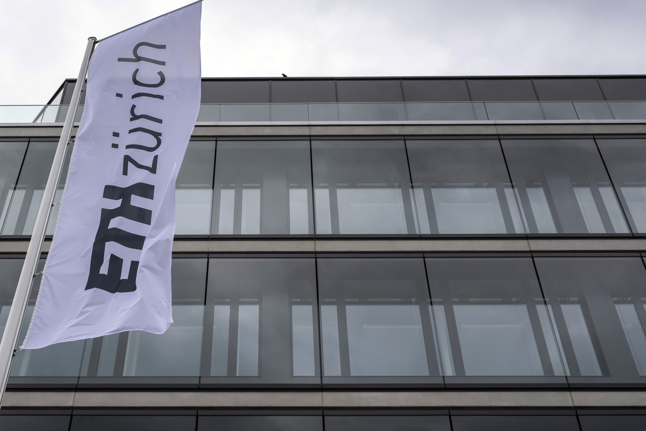a flag with the ETH Zurich logo flies in front of a university building