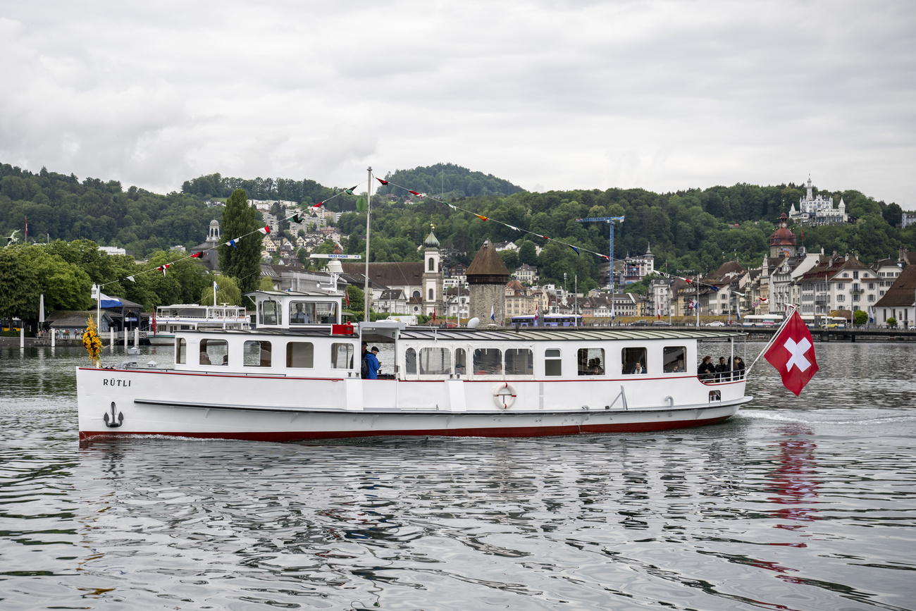 A small ship (the eMS Rütli) is shown sailing on Lake Lucerne.