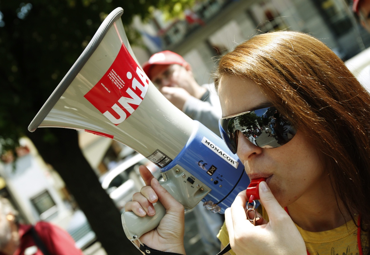 Una manifestante di Unia con megafono e fischietto.