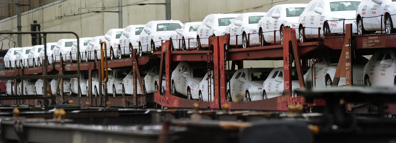 Dozens of new cars are shown loaded onto transport structures.