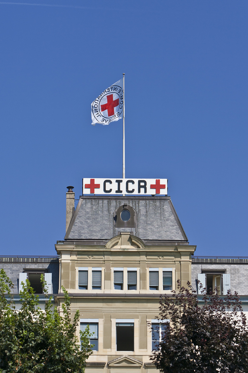 A blowing flag with the emblem of the Red Cross on top of the headquarters of the International Committee of the Red Cross ICRC in Geneva, Switzerland