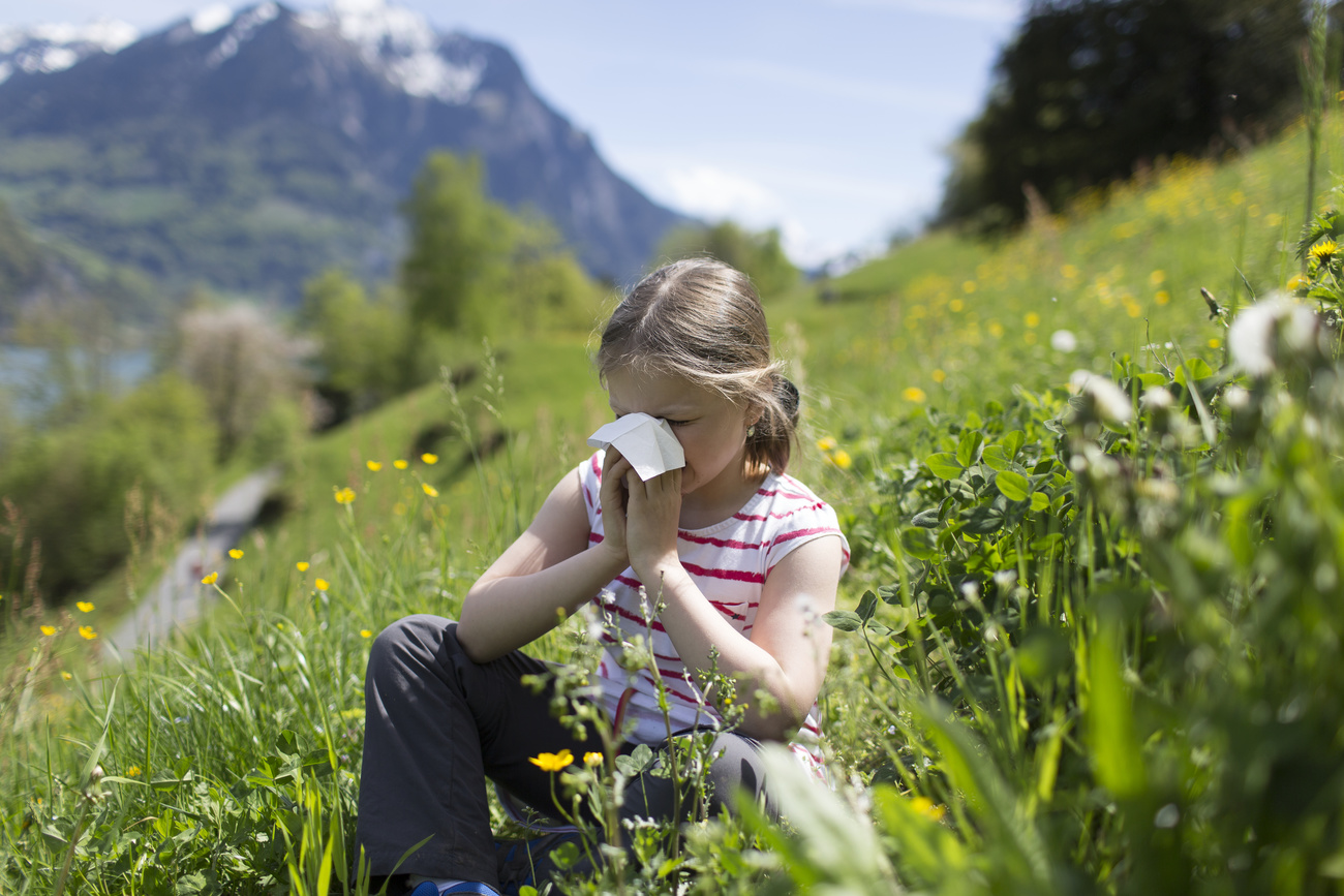 Girl blowing nose in meadow.