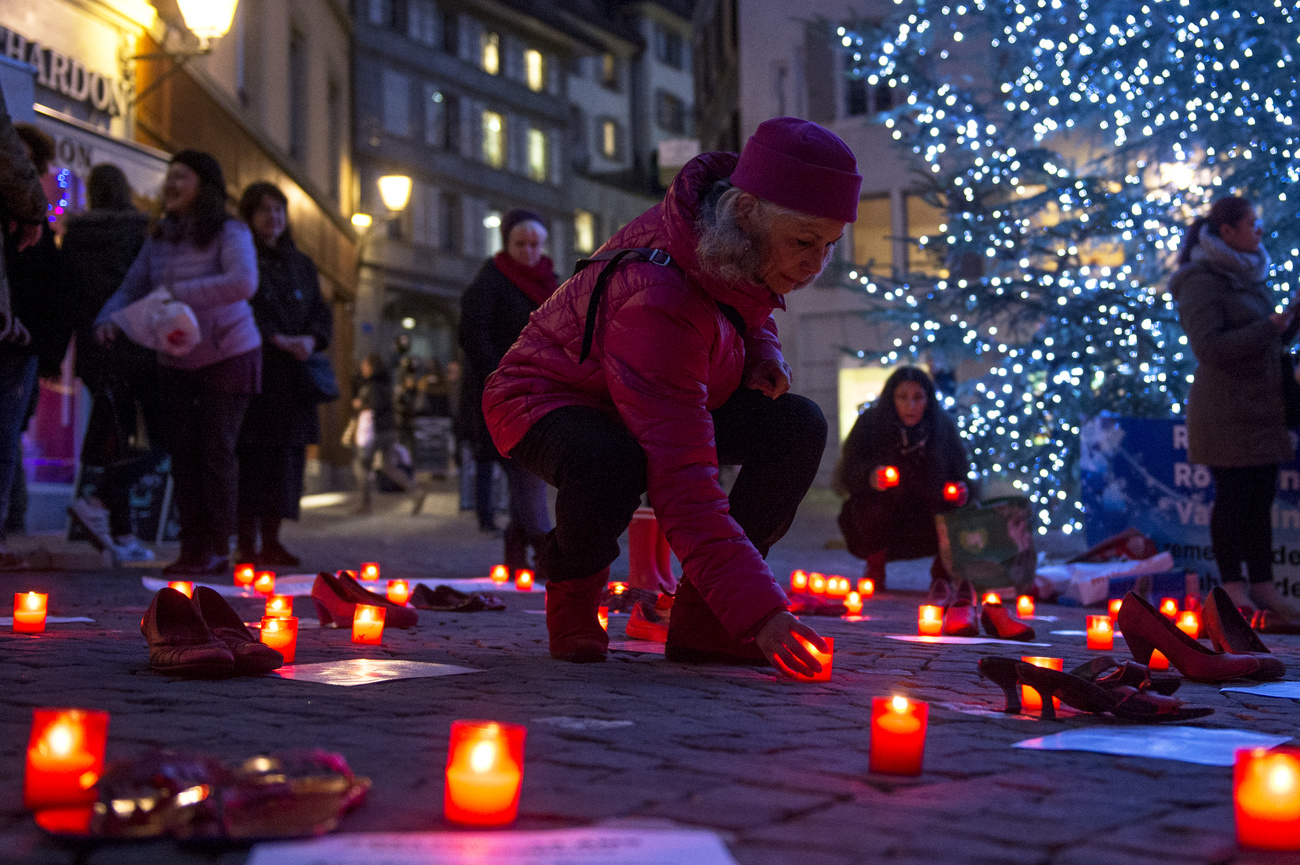 Eine Frau stellt am Freitag, den 25. November 2016, auf der Place Palud in Lausanne eine Kerze auf einen roten Schuh und ein Schild, das Gewalt gegen Frauen anprangert. Bei einer Kundgebung zum Gedenken an die Opfer von Frauenmorden in der Schweiz und an alle Frauen, die Opfer und Überlebende männlicher Gewalt sind, die von Feminista im Rahmen des Internationalen Tages zur Beseitigung von Gewalt gegen Frauen organisiert wurde