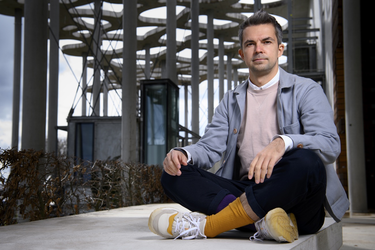 Author Sasha Filipenko poses cross-legged on the floor for a photo.