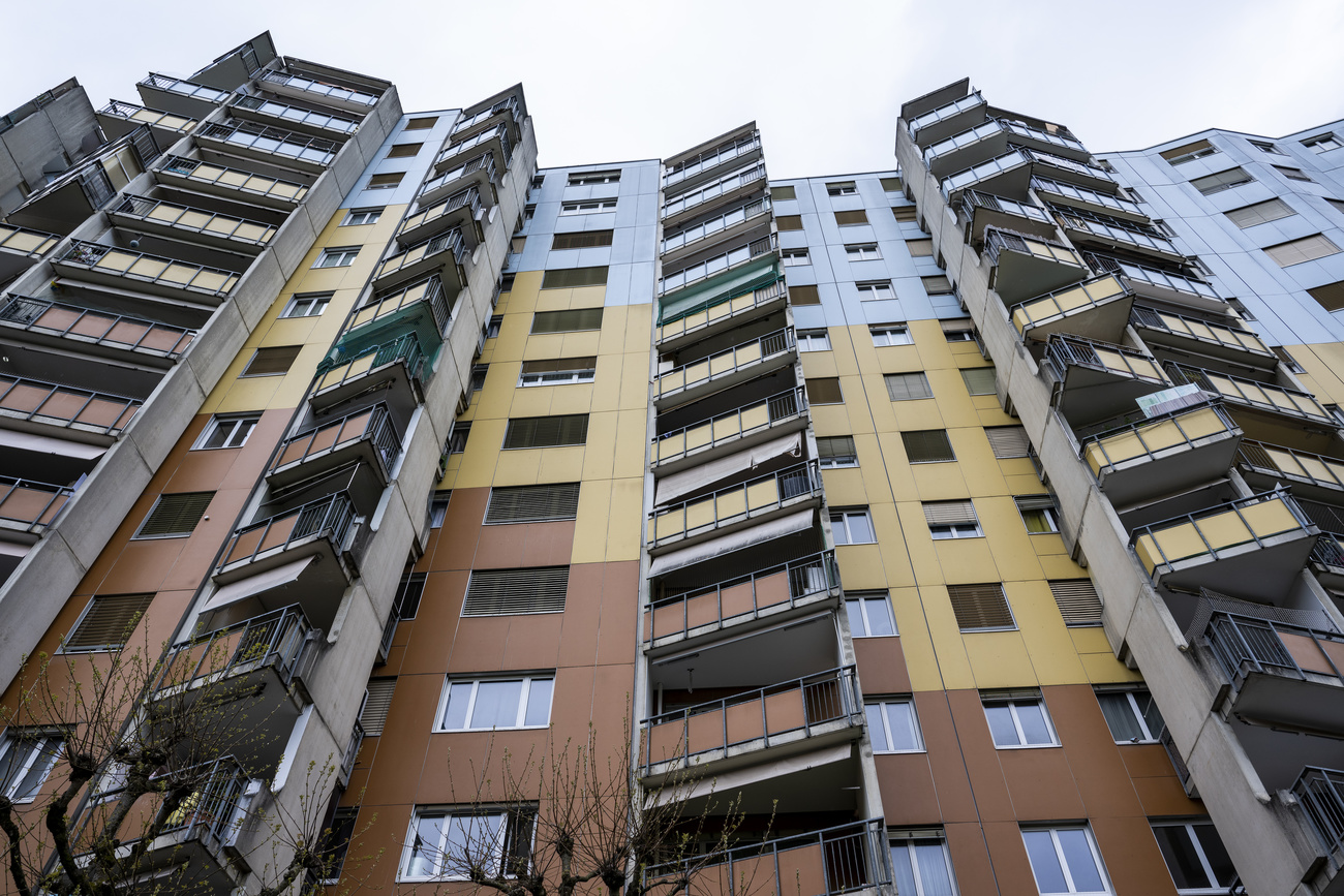 A seven-storey blocks of flats, with a jagged and colourful facade. The bottom part of the building is brown, the middle is yellow and the top is light blue. The balconies stick out at triangular angles.