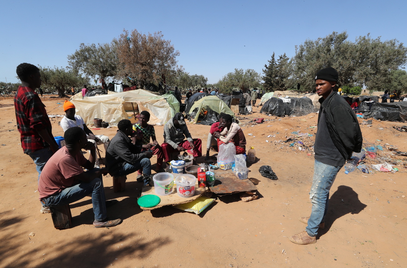 Sub-Saharan African migrants sit near tents at a camp in Jebeniana, Sfax governorate, Tunisia, 04 May 2024. Sfax is one of the main departure points in Tunisia for illegal migration to Europe by boat.
