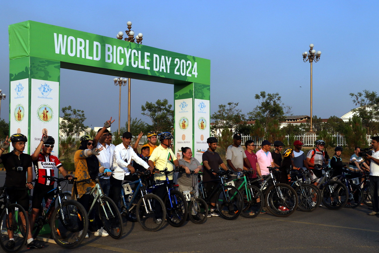 Many people on bicycles stand ready to ride in front of a banner that reads, "world bicycle day 2024"