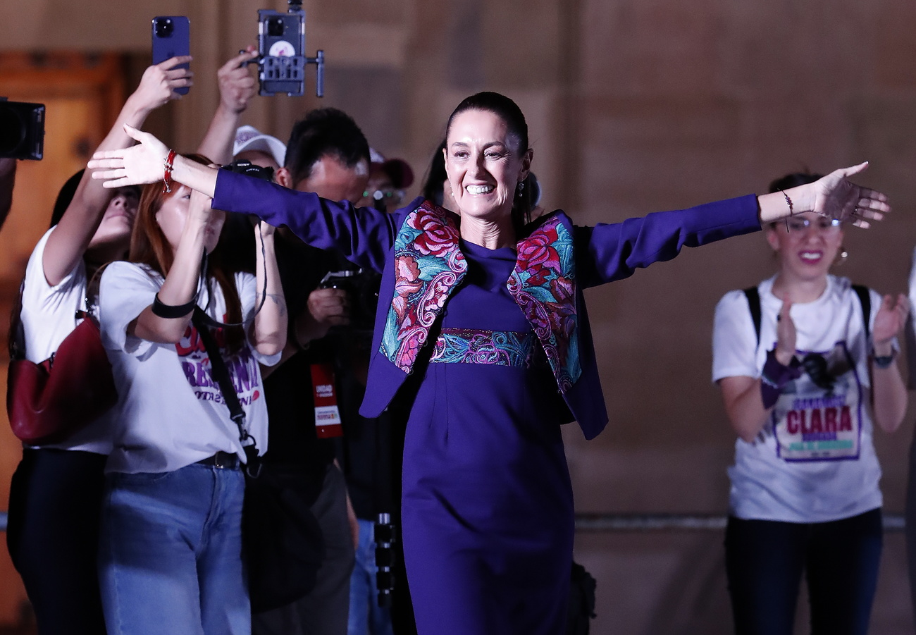 Claudia Sheinbaum sorridente a braccia larghe festeggia la vittoria.