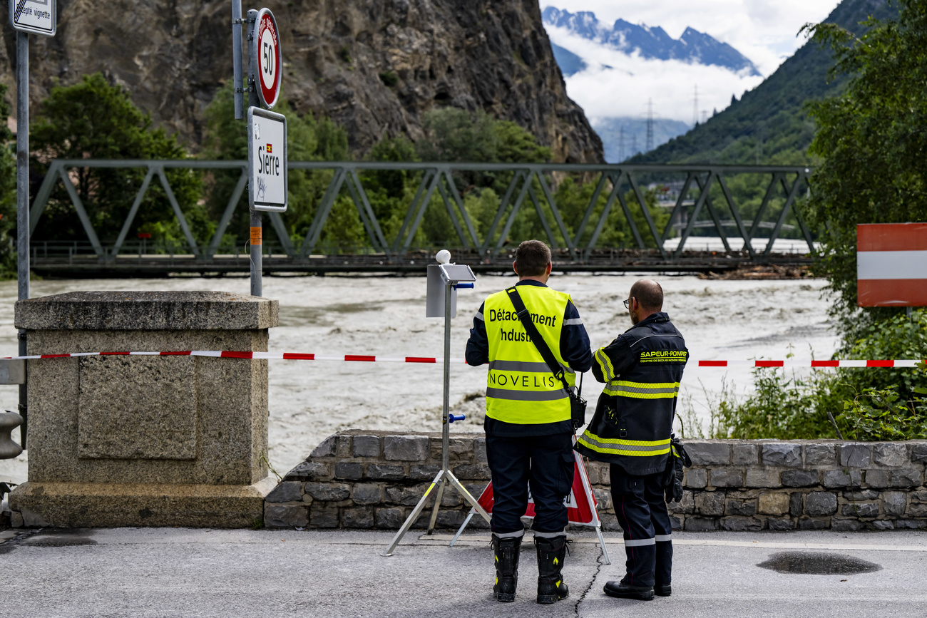 Two firefighters monitor the flow of the Rhone river with some equipment between Sierre and Chippis in Valais on Saturday 22 June 2024.