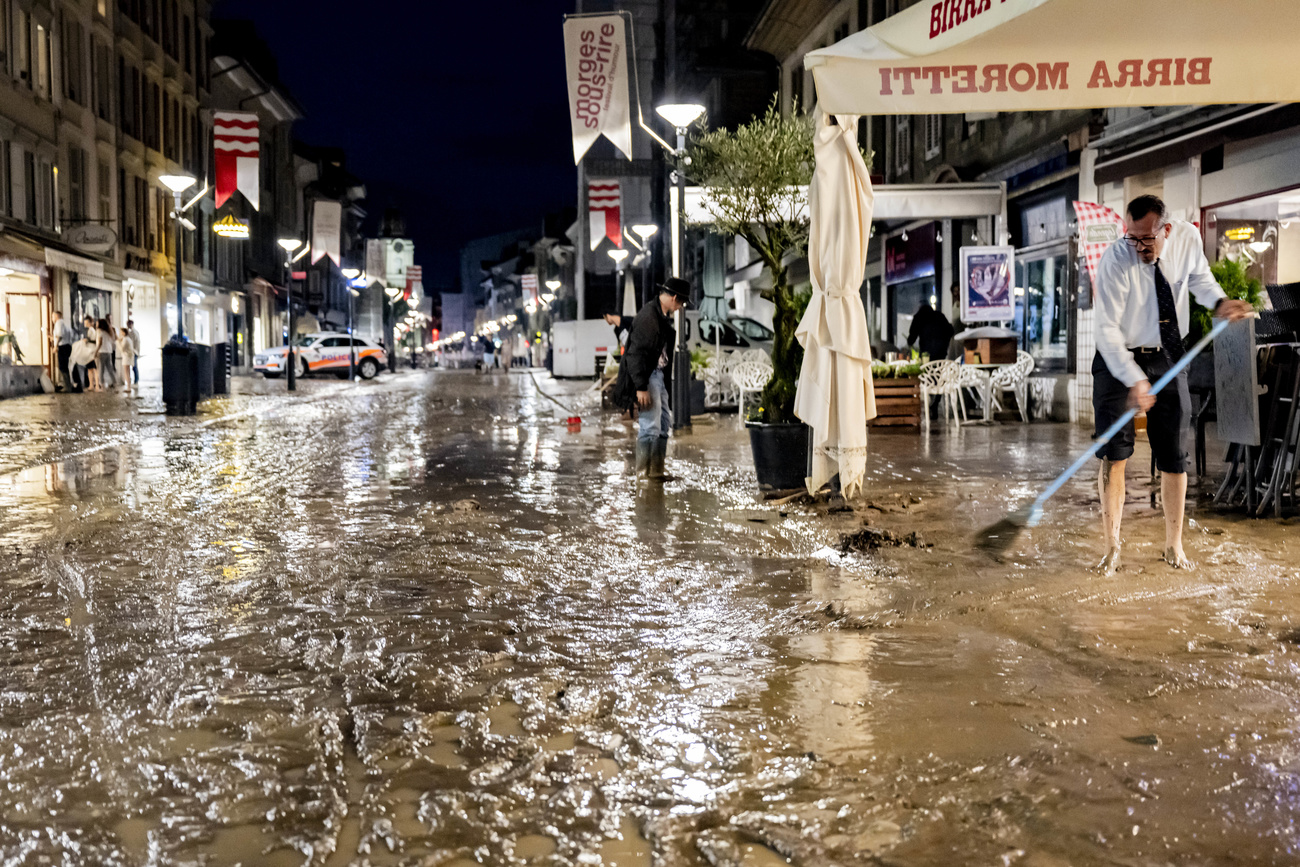 persone spalano fango davanti a un locale