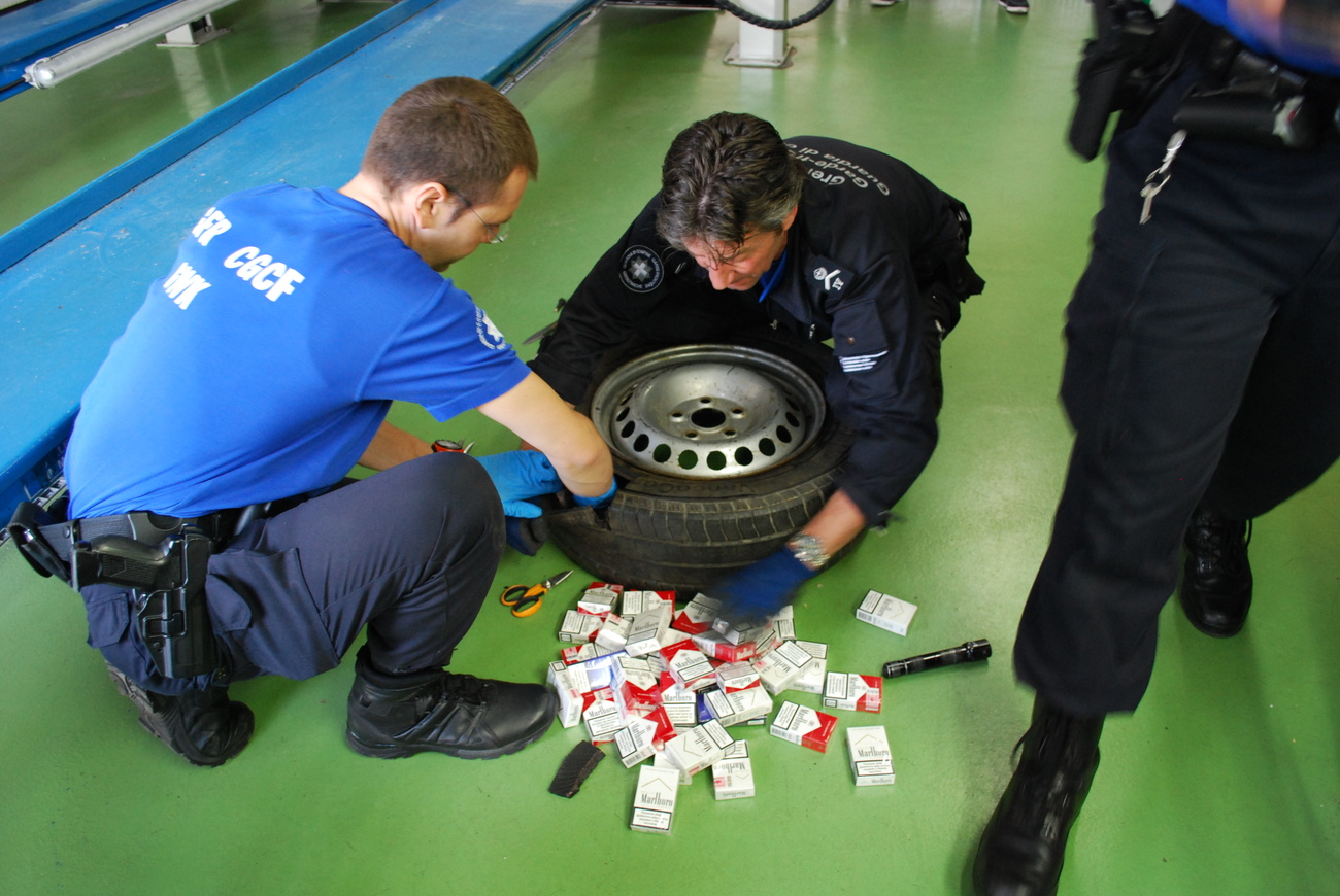 due persone davanti a uno pneumatico e a dei pacchetti di sigarette