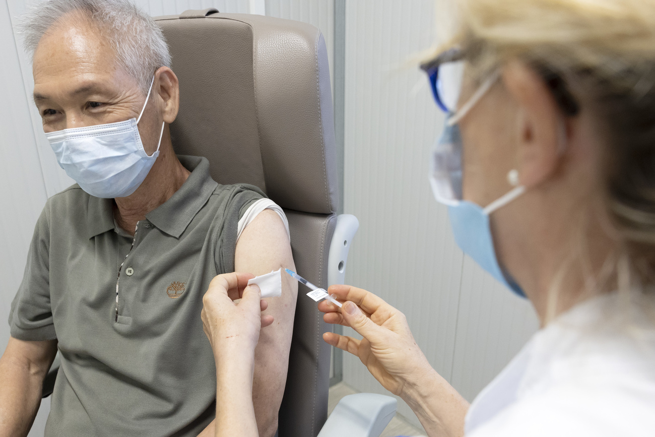 Picture of a doctor preparing to vaccinate an elderly man