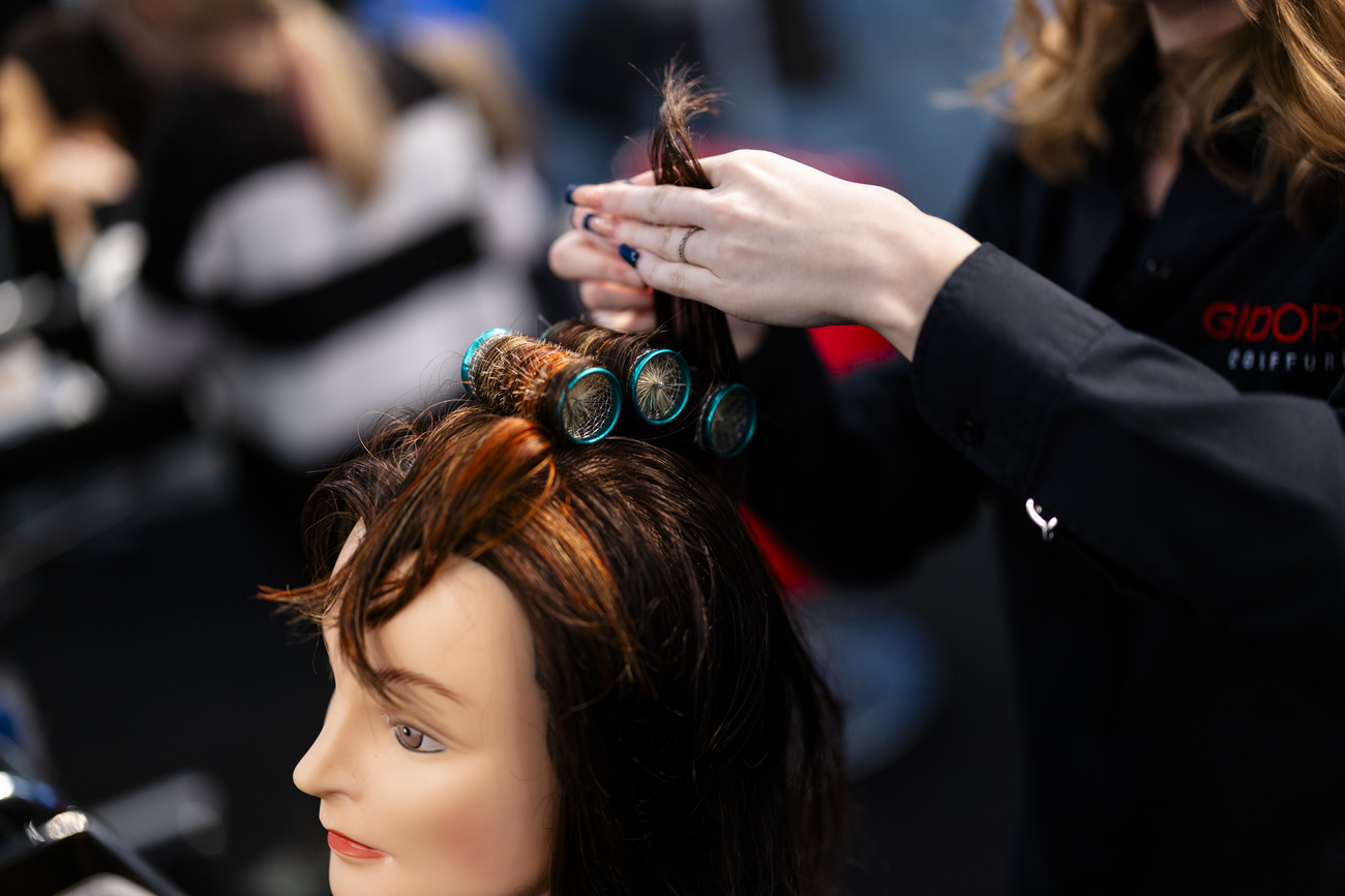 Coiffeuse s'exerçant sur une fausse tête.