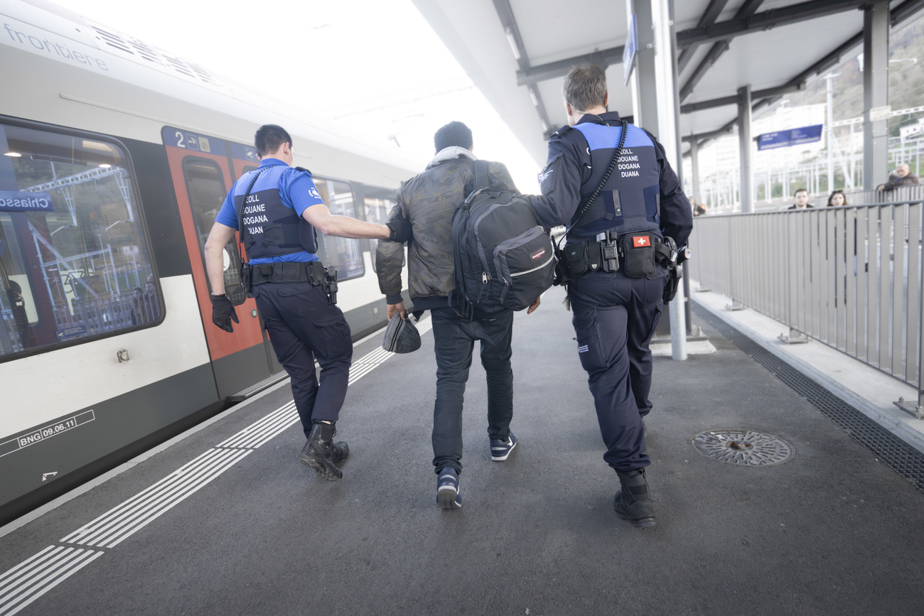Un profugo scortato da due guardie alla stazione di Chiasso.