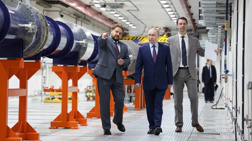 vladimir putin e due persone all'interno dell'istituto di ricerca russo JINR