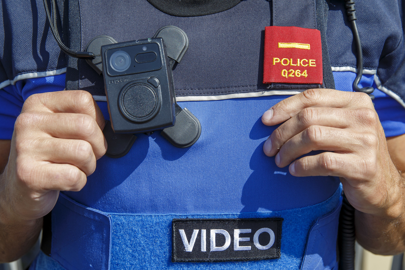 Links im Bild: eine Bodycam, die von einem Polizeibeamten getragen wird.