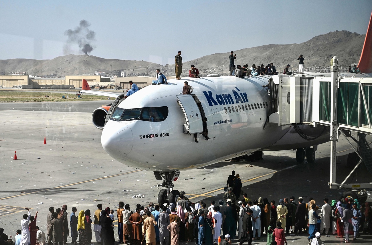 Menschen sitzen auf einem Flugzeug, eine grosse Menschenmenge steht davor