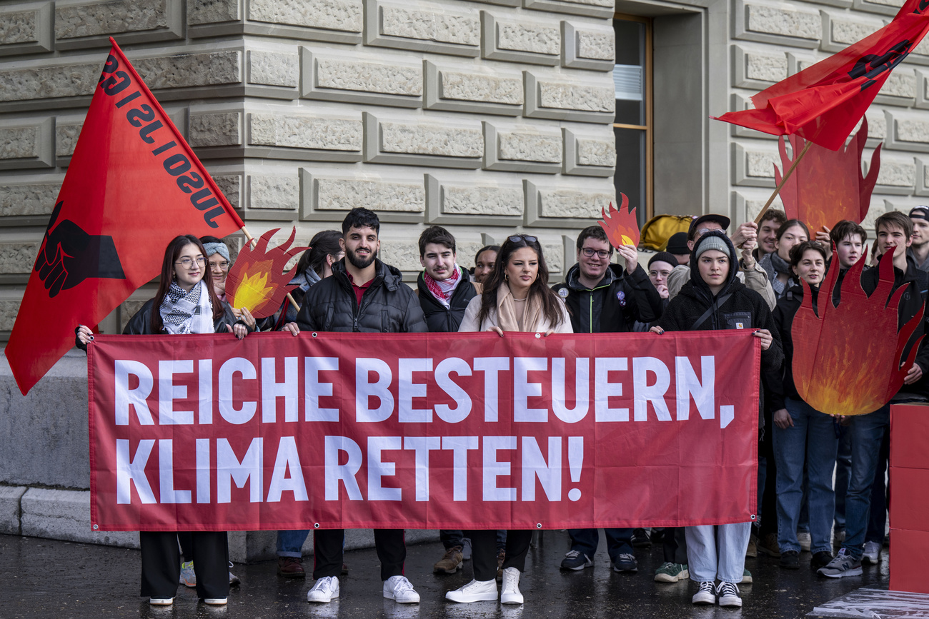 Juso-Mitglieder mit einem Transparent vor dem Bundeshaus. Darauf steht: "Reiche besteuern, Klima retten."