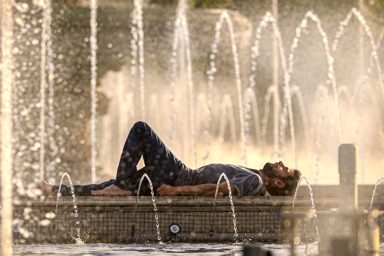 a man lying next to a fountain In the city of Bucharest, Romania, temperatures reached 42 °C this summer. The cisy was hit by a heatwave