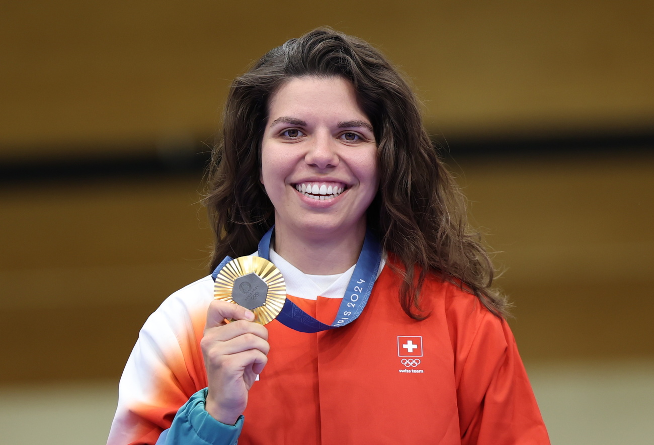 Picture of young woman with brown hair holding a gold medal