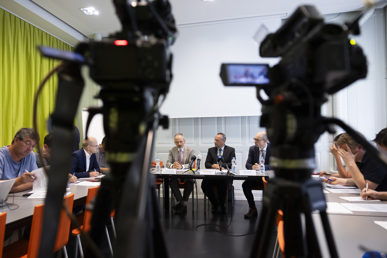 Drei Männer an einer Presseknonferenz